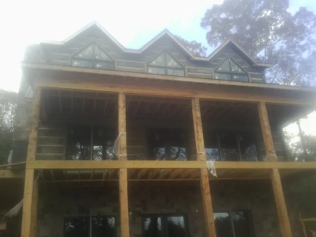 Dormers and porch framing on a large log home under construction — Roof Coating work by our crew in Lima
