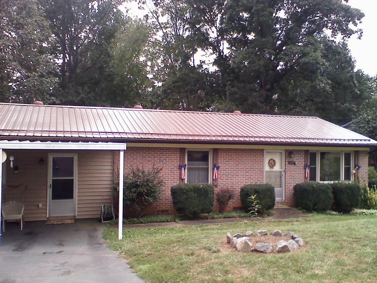 Bronze metal roof and carport on a brick ranch home — Roof Repair work by our crew in Lima
